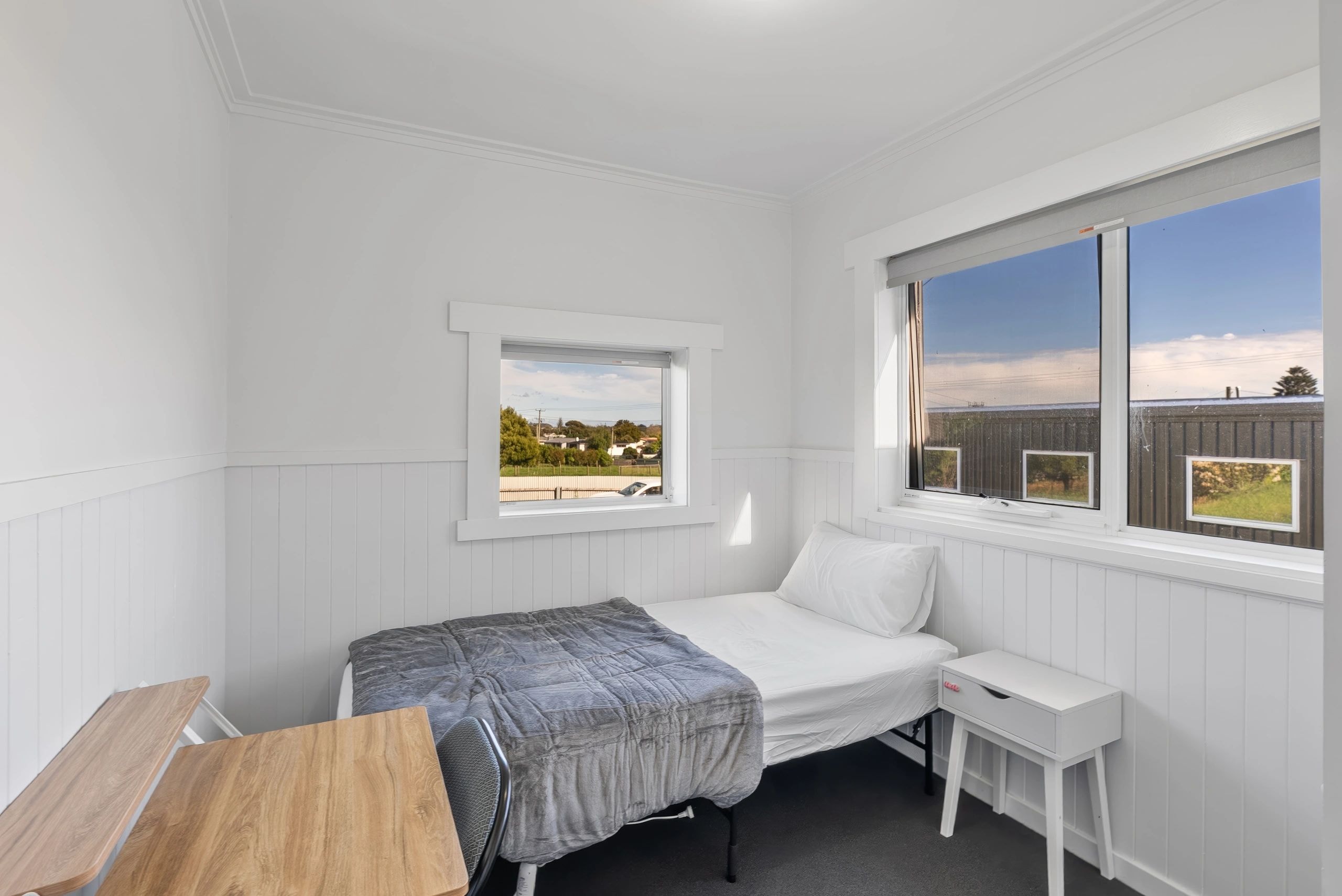 Bright bedroom with white panelling and windows